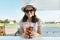 Young teenager girl in hat sunglasses smiling and drinking cool berry cocktail on a hot summer day in outdoor cafe