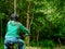 Young teenager girl with long hair on a bike, looking into dark forest. Concept outdoor activity, sport, cycling, Copy space