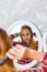 Young teenager girl with long hair combing her hair in front of her mirror.