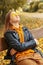 Young teenager girl relaxing and meditating in autumn park sitting on wooden bench