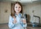 Young teenager girl showing thumbs up sign and holding a transparent glass. Child recommend drinking water. Good healthy habit for