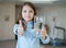 Young teenager girl showing thumbs up sign and holding a transparent glass. Child recommend drinking water.  Good healthy habit