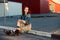 Young teenager girl sitting on the road outside near urban red wall background in skirt and jeans jacket on the sunset.