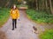 Young teenager girl walking with her Yorkshire terrier on retractable leash on a path in a park, Selective focus. Concept pet, and