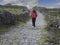 Young teenager girl walking up a hill on a rough small country road between stone fences. Aran Island, Ireland. Travel and tourism