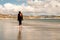 Young teenager girl walking on a warm sand of Gurteen beach, county Galway, Ireland. Warm sunny day. Cloudy sky. Outdoor activity