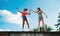 Young teenager girls friends outdoors in city, standing on concrete wall.