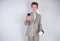 Young teenager with surprised emotions in grey business clothes standing with mobile phone and paper cup of coffee on white studio