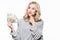 Young thinking pretty woman in grey sweater holding bunch of Euro banknotes, looking upwards with hand on chin, isolated on white.