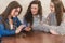 The young three good girls are sitting in a cafe and spend time communicating.