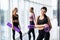 Young three Women taking break after workout session. Group of females in sportswear with exercise mat at gym