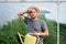 Young tired farmer wiping off his sweat after working in a greenhouse