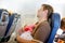 Young tired father and his baby daughter sleeping during flight on airplane going on vacations