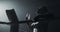 Young tired man drinking from the water bottle after training in the dark boxing ring with smoke. Silhouette. Boxing