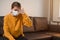 Young tired unhealthy woman sitting on a sofa in a living room at home with her eyes closed