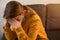 Young tired unhealthy woman sitting on a sofa in a living room at home with her eyes closed