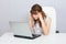 Young tired woman working with laptop at table