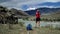 Young torist woman is standing to the edge of the mountain and taking photo scenic landscape. Back view, slider