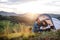 Young tourist couple travellers with tent shelter sitting in nature, drinking coffee.