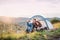 Young tourist couple travellers with tent shelter sitting in nature, taking selfie.