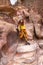 A young tourist girl with a backpack stands on a stone at the bottom of the canyon