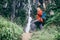 Young tourist man with backpack near the waterfall in rainy mountain forest