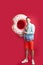 young tourist man holds inflatable ring look camera isolated on red background.
