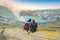 Young tourist man and woman sit at the edge of the crater of the Ijen volcano or Kawah Ijen on the Indonesian language