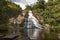 Young tourist men in the Sunny day in the Tropical waterfall falls from the mountain