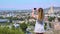 A young tourist in a short gray dress and long blond hair stands on the edge of a cliff and makes amazing bright photos