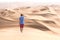 Young tourist in shorts hiking in giant dunes.