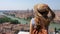 Young tourist woman with hat and backpack enjoying cityscape of Verona, Italy. Back view.
