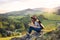 Young tourist woman traveller with backpack sitting in nature, writing notes.