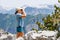 Young tourist woman watching birds in the mountains. Slim hiker birdwatcher girl with binoculars