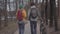 Young tourists walking in the park with backpacks on their backs. The man leads the bicycle and woman in bright yellow