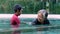 Young trainer helping senior woman in aqua aerobics and working out in the pool. old woman and mature man doing aqua aerobics