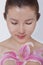 Young tranquil woman looking down at a large pink flower, studio shot