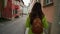 Young travel woman in yellow coat with backpack is walking on the beautiful old cozy german street