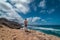 Young traveler crosses the dunes of the jandia natural park in fuerteventura canary islands and contemplates in the background t