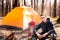 A young traveler in the forest is resting near the tent and cooked breakfast in nature