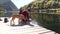 Young traveler hiker with backpack giving water to dog on the lake.