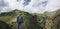 Young Traveler Man Standing On Top Of Cliff In Mountains And Enjoying View Of Nature, Rear View