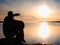 Young traveler man at sunset. Tourist sitting on the cliff above lake