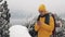 Young traveler man using smartphone in hiking winter tour. Snowy blurred mountains cape and lake. Traveling and