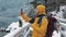 Young traveler man using smartphone in hiking winter tour. Snowy blurred mountains cape and lake. Traveling and