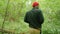 Young Traveler Man Walking in the Forest. Rear back view of hiker walking on trek through green park. Caucasian Mixed