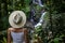 Young traveler woman wearing hat, enjoying tropical forest landscape with waterfall, Ubud, Bali. Pengibul waterfall. View from