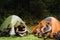 Young travelers resting in tents while hiking in green forest