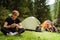 Young travelers resting in tents while hiking in green forest