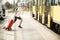 Young traveller man in hat with suitcase running by train station. Tourist late on plane trip